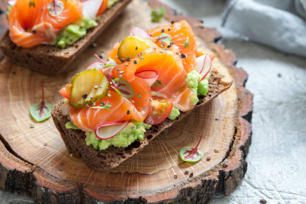 istock Smorrebrod with salmon on rye bread with vegetables and herbs 932726512