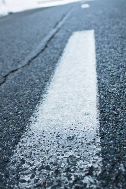 istock close up of white line on empty road cracked asphalt 932729230