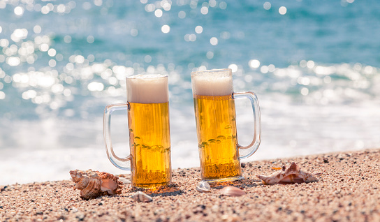 Beer glasses on the beach with blurred background of the sea.