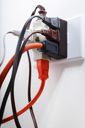 White double outlet installed on pink wall with inserted black electrical plug, front view.