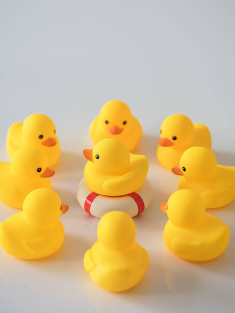 istock Yellow rubber duck on an inflatable life saving ring with many other yellow ducks surrounding it. 932743084