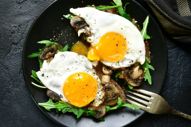 istock Whole grain toasts with sauteed mushrooms, fried eggs and arugula leaves 932746912