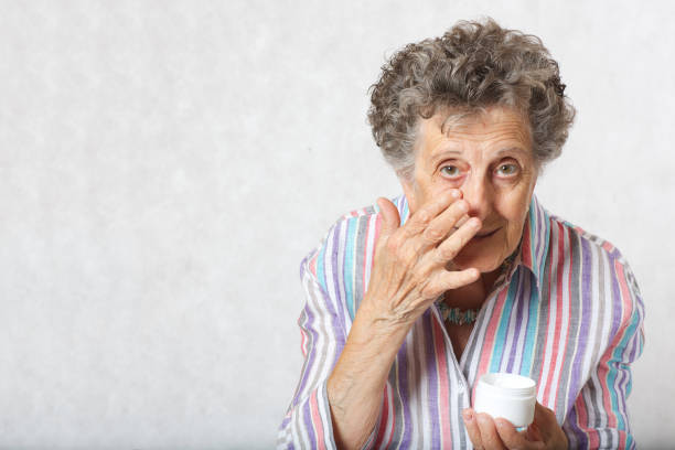 istock Senior woman uses face cream 932750064