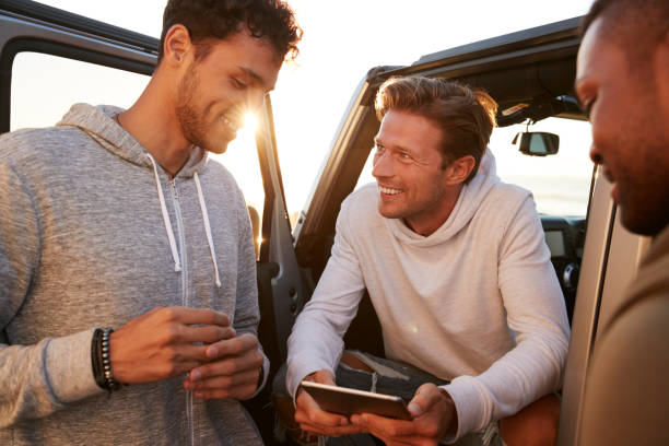 istock Three male friends on a road trip using a tablet, close up 932750544