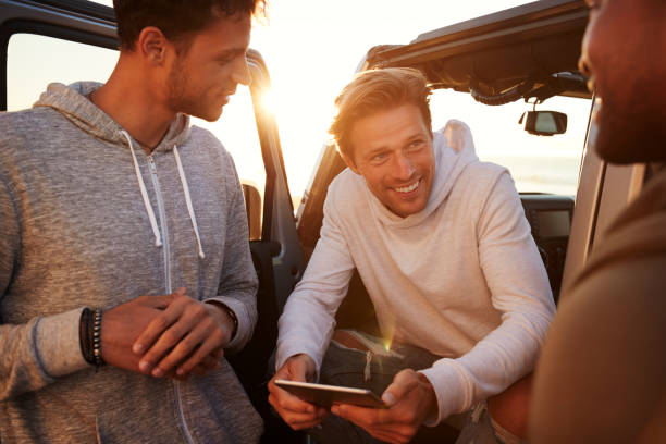 istock Three male friends on a road trip using a tablet, close up 932750564