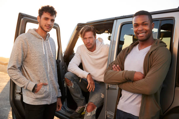 istock Three male friends on road trip looking at camera from jeep 932750580