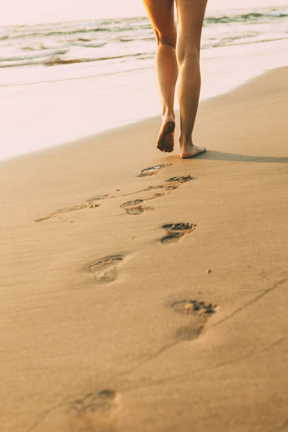 istock Low section view of a woman walking on the beach 932750706