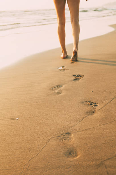 istock Low section view of a woman walking on the beach 932750722