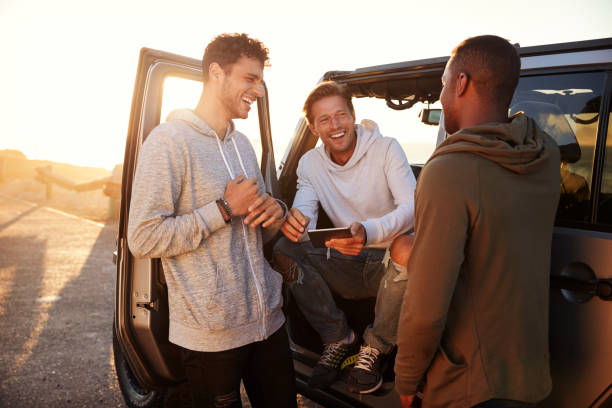 trois amis de sexe masculin sur un road trip à l’aide d’une tablette pc - seulement des hommes photos et images de collection