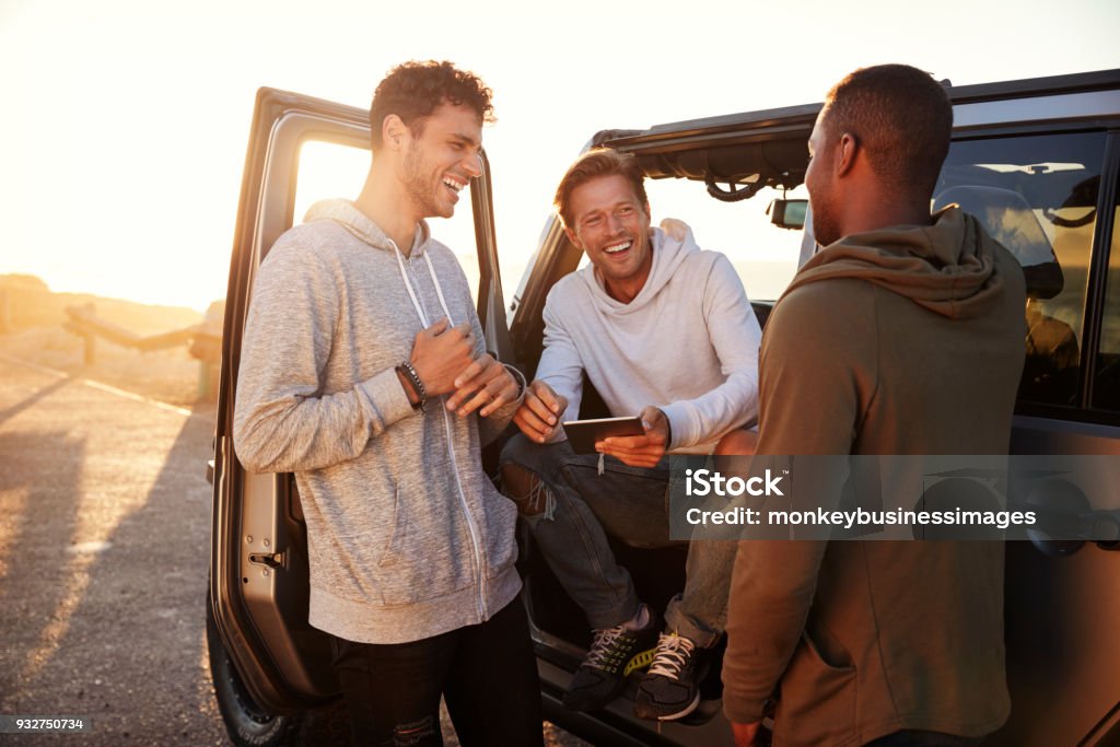 Three male friends on a road trip using a tablet computer Friendship Stock Photo