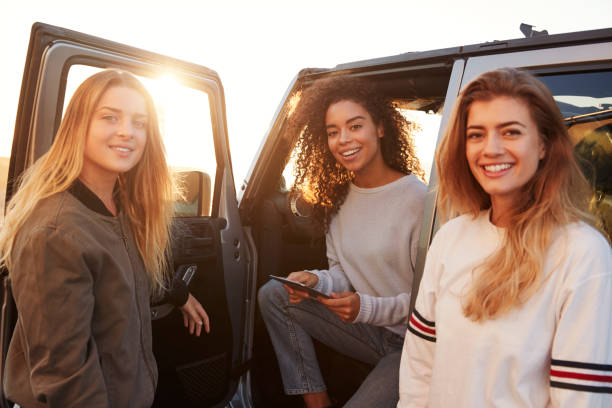 istock Three female friends on a road trip using a tablet, close up 932750736