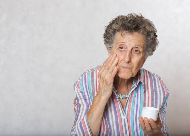 istock Senior woman uses face cream 932750764