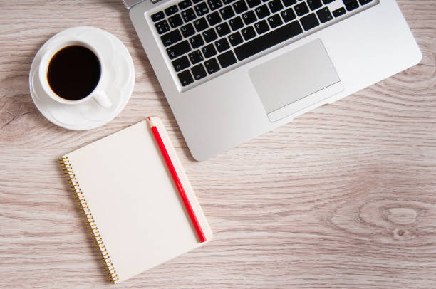 istock Notepad, laptop and coffee cup on wood table 932750894