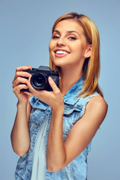 istock Smiling blond female holds compact digital photo camera. 932750950
