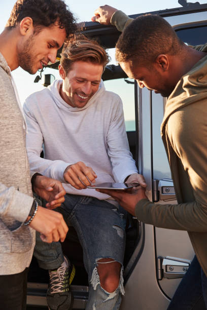 istock Male friends planning road trip with tablet computer, vertical 932751202