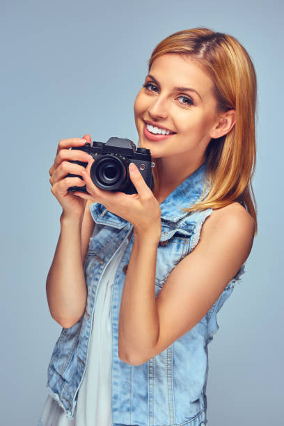 istock Smiling blond female holds compact digital photo camera. 932751226