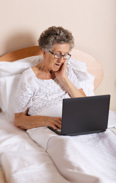 istock Senior woman is using her laptop being in the bed 932752160