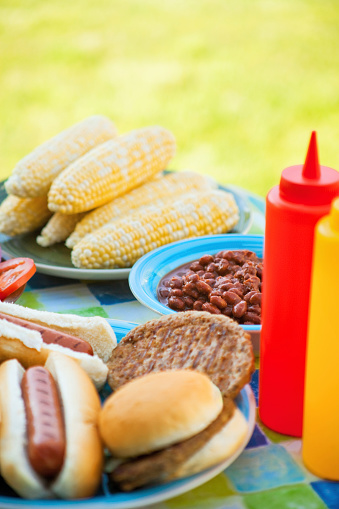 Hot dogs, hamburgers and condiments outdoors in the summer