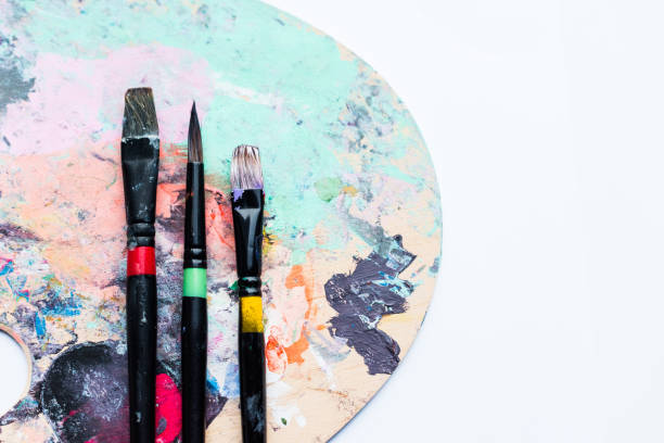 istock Artistic brushes on palette covered with colorful paint spots 932758722