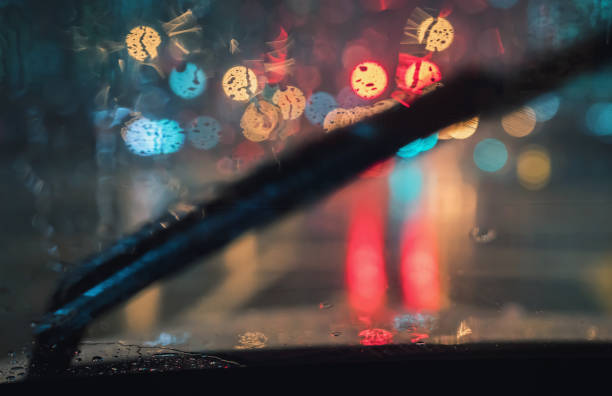 windshield wiper is wiping on car front window in rainy night. intended defocused image.