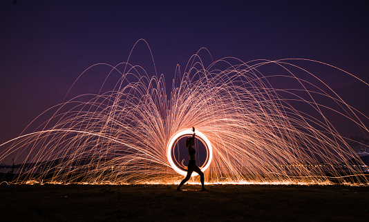 Silhouette Asia woman yoga on the beach at sunset with Steel wool spinning background