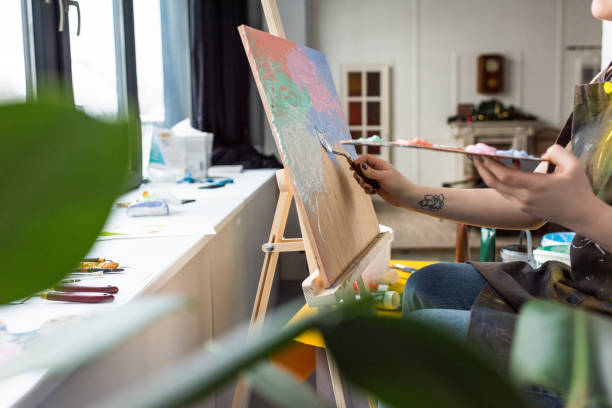 istock Close-up view of young creative girl applying primer on canvas in light studio 932760352