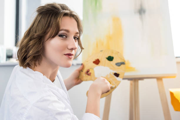 istock Young artistic girl mixing paint in light studio 932760602