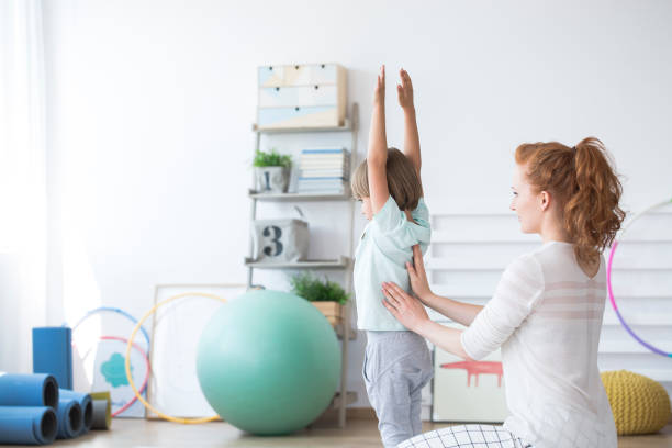 Psychiotherapist with young boy Psychiotherapist with a young boy doing exercise in a clinic deformed stock pictures, royalty-free photos & images