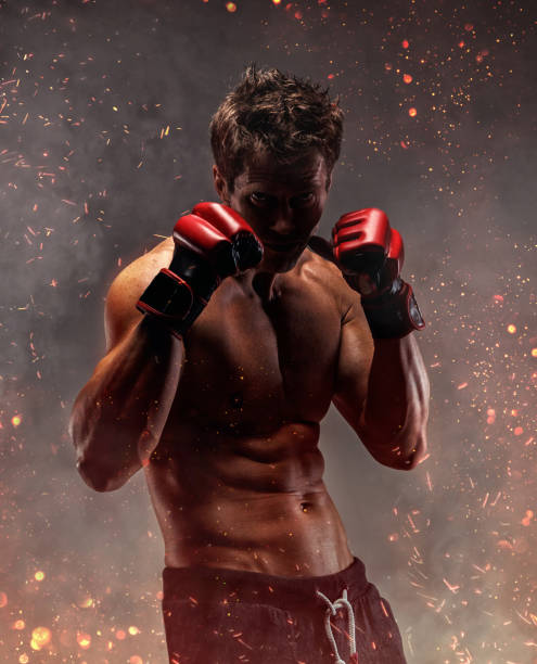 Fighter with naked torso poses in studio. Portrait of fighter in fire sparks and smoke. violence boxing fighting combative sport stock pictures, royalty-free photos & images