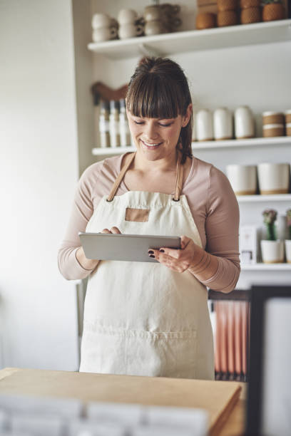 istock Smiling florist standing in her flower shop using a tablet 932767566