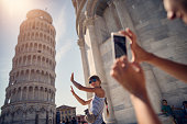 holding up photos of the Leaning Tower of Pisa
