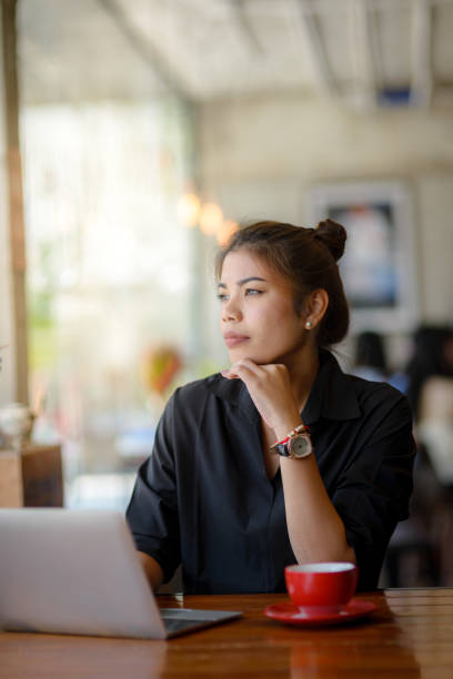 istock Asian woman working in cafe and looking out window. 932771614