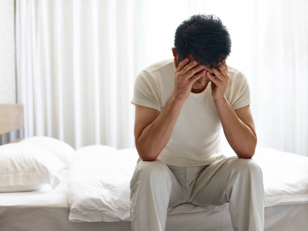 istock frustrated asian man sitting on bed in bedroom 932771814
