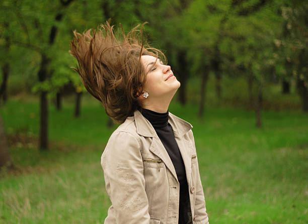 Horizontal outdoor shot of young blonde woman with feathers in her hair.