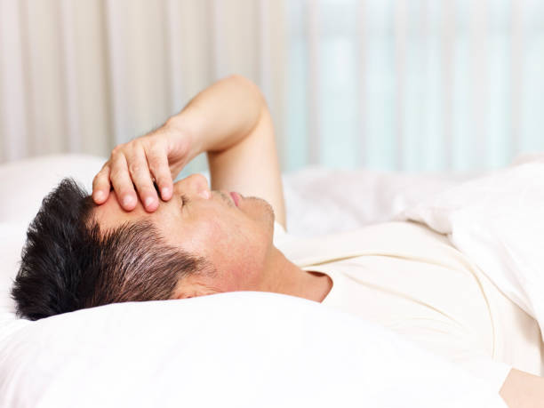 istock tired asian man lying in bed 932774432