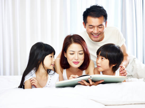 istock asian parents and two children reading book together 932775354
