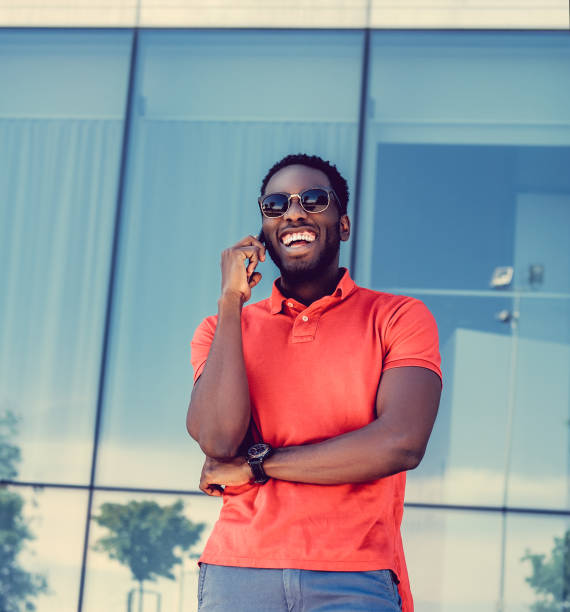 homem negro sorridente vestindo uma camisa polo vermelha. - polo shirt african ethnicity men african descent - fotografias e filmes do acervo