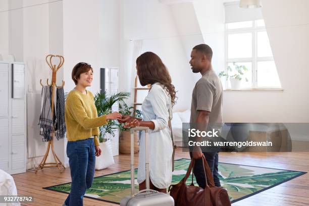 Asian Woman Welcomes Young Black Couple Into Her Home Stock Photo - Download Image Now