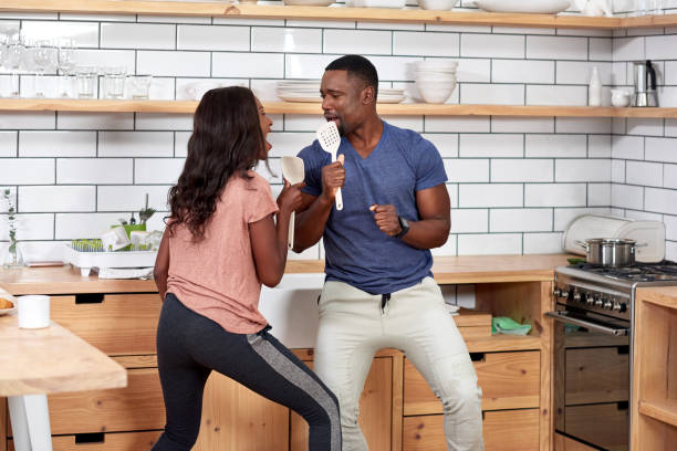 istock Happy African black couple having fun dancing and singing in their kitchen 932778876