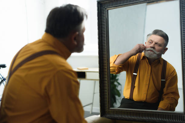 istock handsome bearded senior man adjusting moustache and looking at mirror 932778946