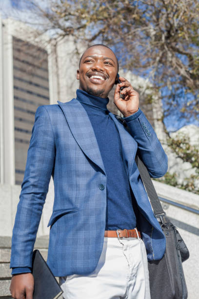 istock Well dressed businessman talking on his mobile phone while standing on steps in the city. 932782232