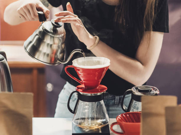 giovani donne barista al lavoro in un bar. preparazione versare sopra il caffè - pouring coffee human hand cup foto e immagini stock