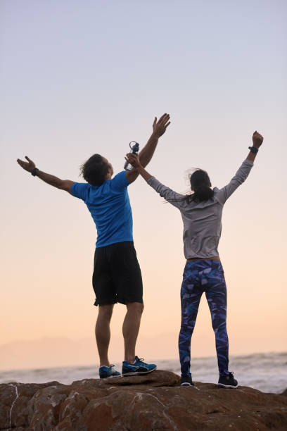 istock Happy active couple at sunset on the beach celebrating a good run 932797936
