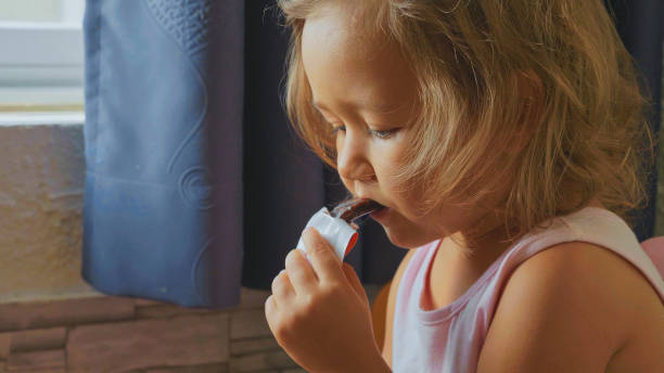 istock Little cute child girl eats fruit bar 932798700