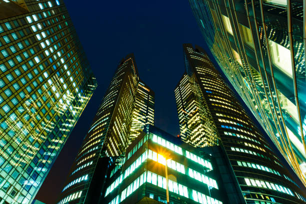 Night city lights, skyscrapers glass facades. Modern urban architecture, economy, finances, business activity concept.