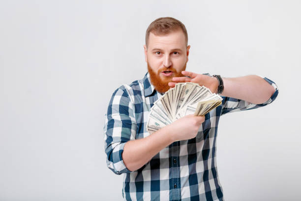 istock man with beard holding lot of hundred-dollar bills 932805696