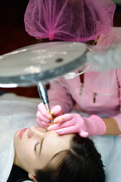 istock doctor cosmetologist doing machine coloring of eyebrows 932809656