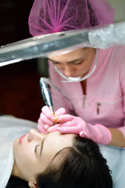 istock doctor cosmetologist doing machine coloring of eyebrows 932809700