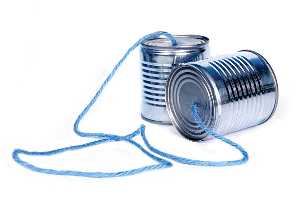 Two tin cans connected with string forming telephone stock photo