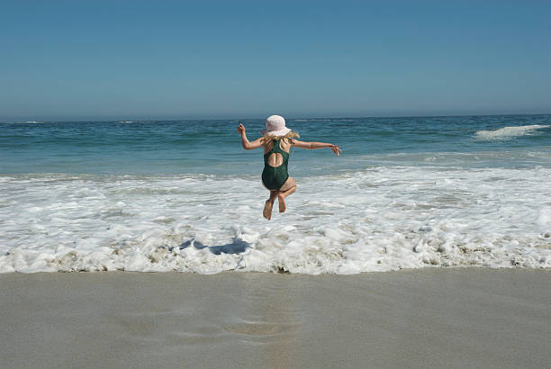 Girl jumping over waves. stock photo